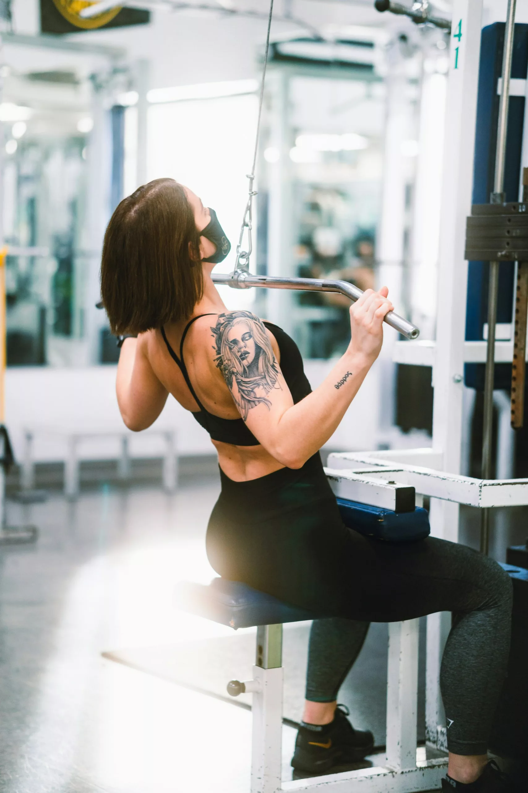 woman in black tank top and black leggings sitting on exercise equipment